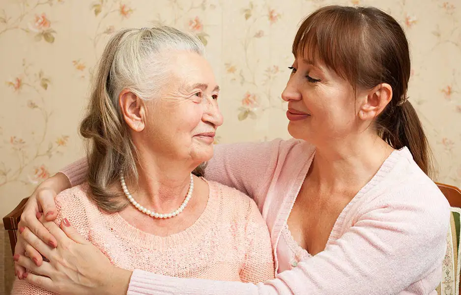 an elderly woman and a middle
    aged woman smiling at each other